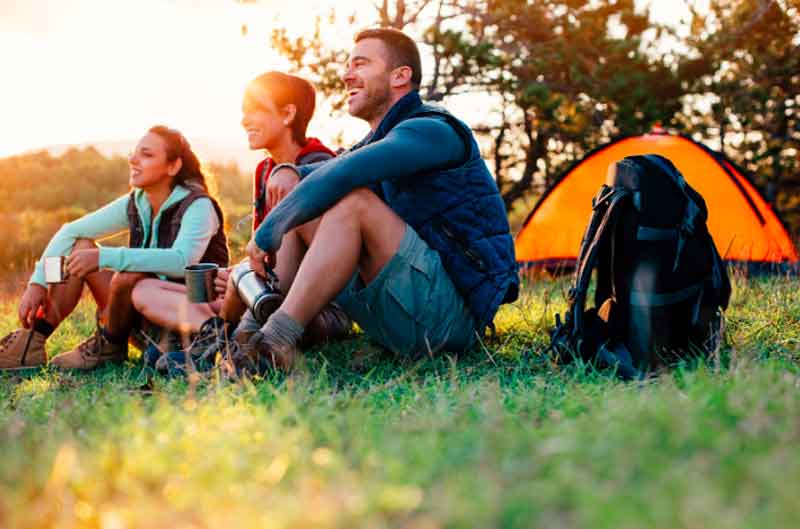 Friends Sitting in Grass Near a Tent