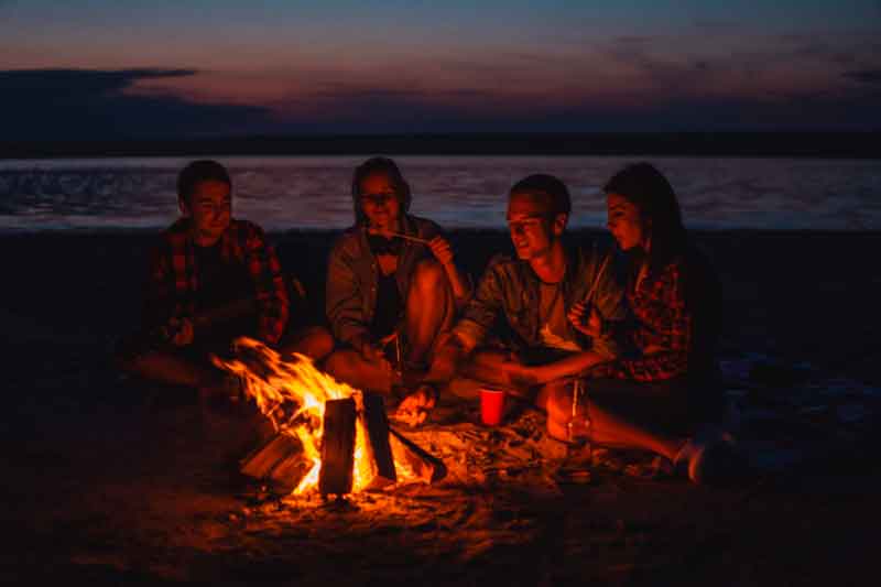 Friends chilling near a beach bonfire