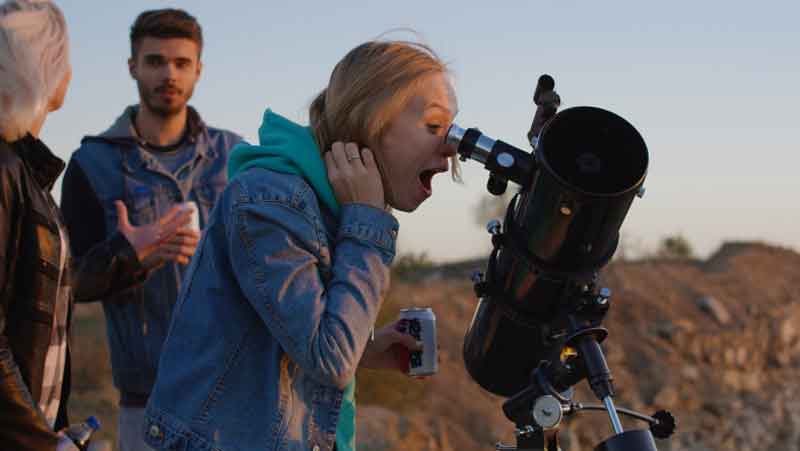 Girl stargazing through a telescope