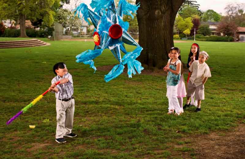 Kids at a fiesta hitting a pinata