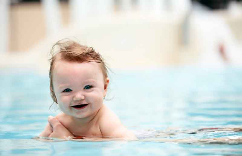 1 year old in a pool smiling