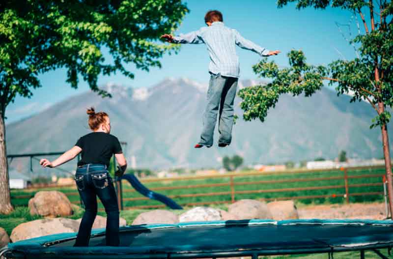 Girl and boy jumping on trampoline