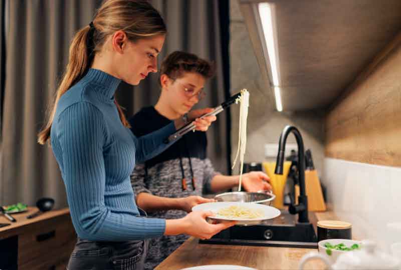 Teenagers cooking pasta
