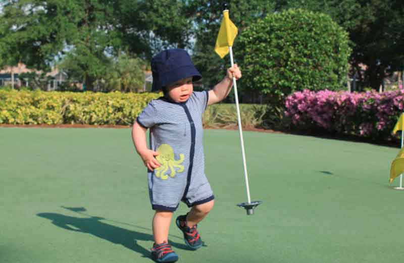 Young boy holding a golf flagpole